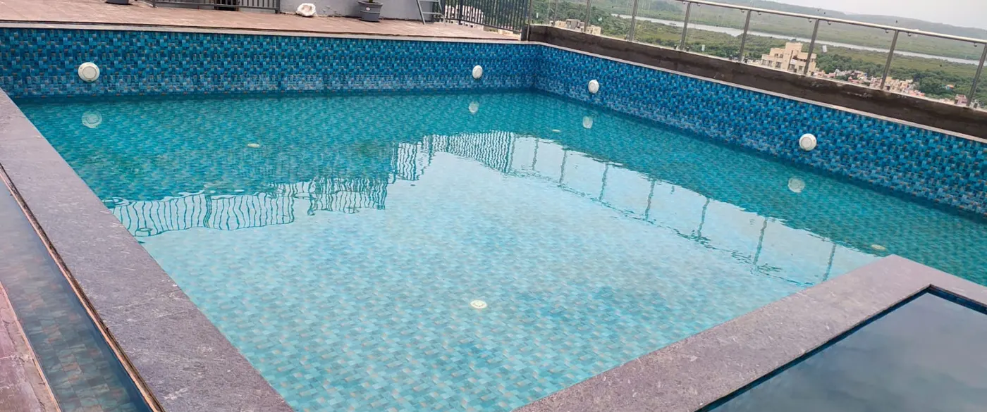 Rooftop swimming pool with blue mosaic tile walls, underwater lights and stone coping